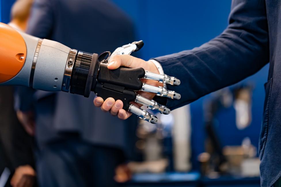 Webshops und APIs: Mann schüttelt einem Roboterarm die Hand